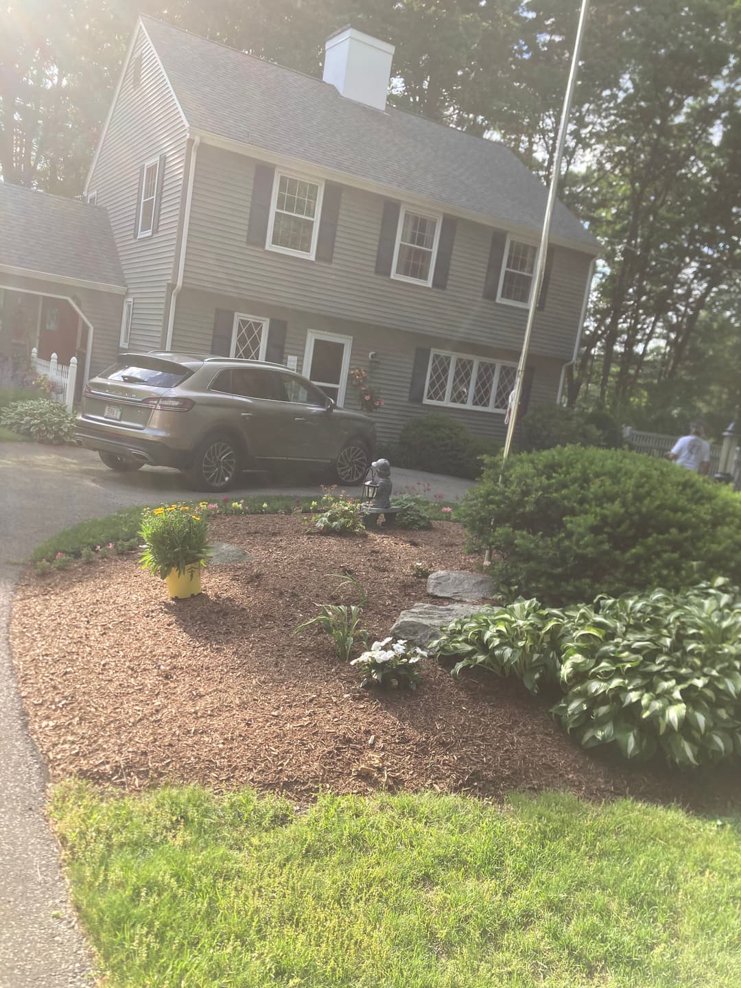 House with gray siding, landscaped garden, car parked in driveway, and garden gnome.